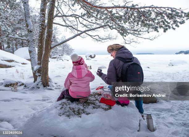 父親和嬰兒在海灣旁野餐。全家人喝熱茶，喜歡交談和自然。 - finland 個照片及圖片檔