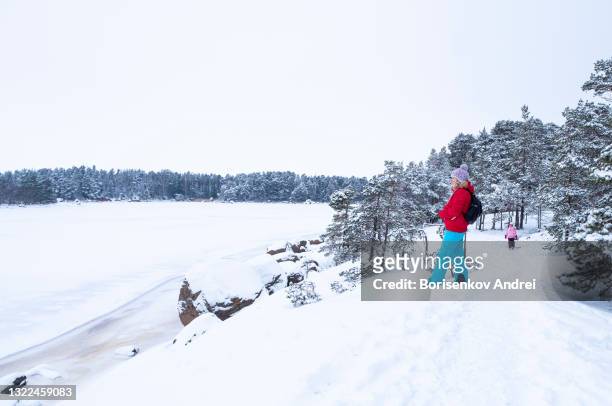 a caucasian family, a woman of 40 years old and a daughter of 5 years old, are walking in the winter forest on the shore of the bay. - finnland winter stock pictures, royalty-free photos & images