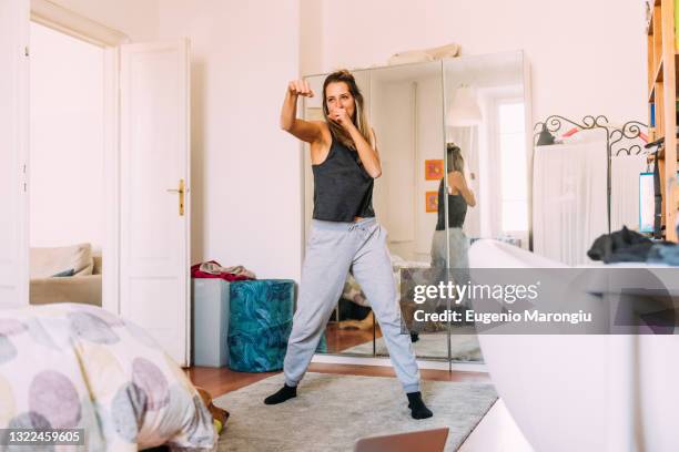 italy, young woman exercising at home - fighting stance stock pictures, royalty-free photos & images