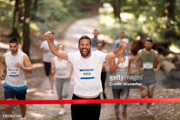 exitoso corredor de maratón cruzando la línea de meta con los brazos en alto. - fun run fotografías e imágenes de stock