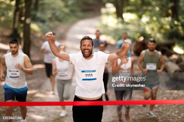 successful marathon runner crossing finish line with arms raised. - maratona imagens e fotografias de stock