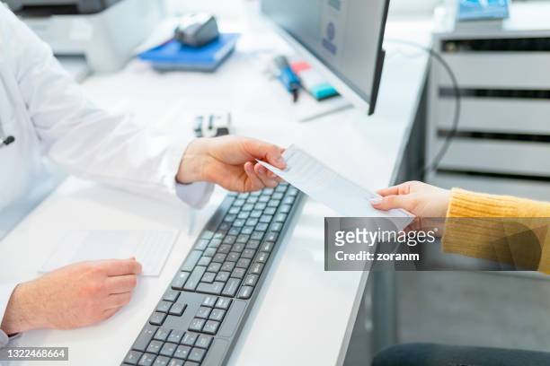 passing prescription to patient over the desk - referral stock pictures, royalty-free photos & images