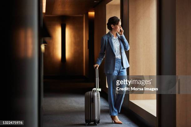 businesswoman with luggage talking on smart phone - lobby foto e immagini stock