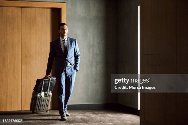 businessman walking with luggage in hotel - rolling luggage stock pictures, royalty-free photos & images