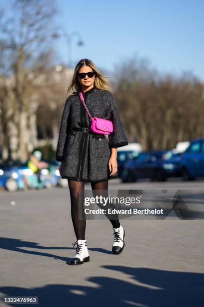 Thassia Naves wears sunglasses, earrings, a Chanel 19 neon-pink crossbody bag, a heather dark-grey tweed coat with a black trim, a Chanel black...