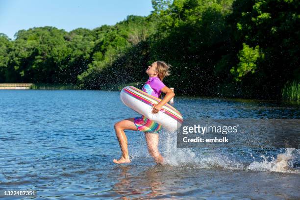 girl with swim ring running into lake water - 11 loch stock pictures, royalty-free photos & images