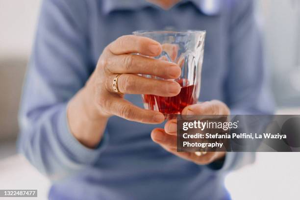 senior woman holding a glass of fruit juice/wine - cranberry juice stock pictures, royalty-free photos & images