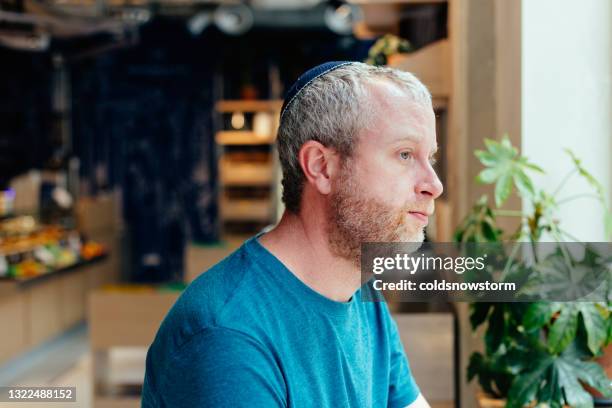 jewish man wearing skull cap inside coffee shop in the city - religious symbol stock pictures, royalty-free photos & images