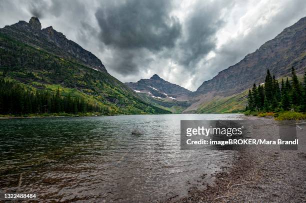 lake upper two medicine lake, mountain peaks lone walker mountain and mount rockwell in the background, dramatic clouds, glacier national park, montana, usa - two medicine lake montana stock pictures, royalty-free photos & images