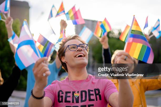 attivista lgbtq+ che tiene le bandiere arcobaleno tra le mani e guarda in alto verso il cielo - giustizia sociale foto e immagini stock