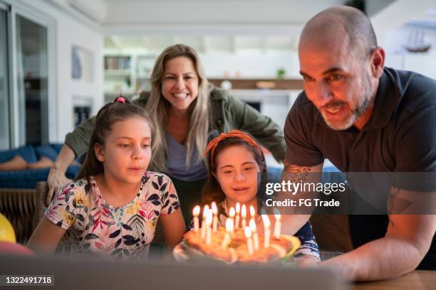 girl blowing candles on birthday cake during virtual celebration at home - including a special needs girl - zoom birthday stock pictures, royalty-free photos & images