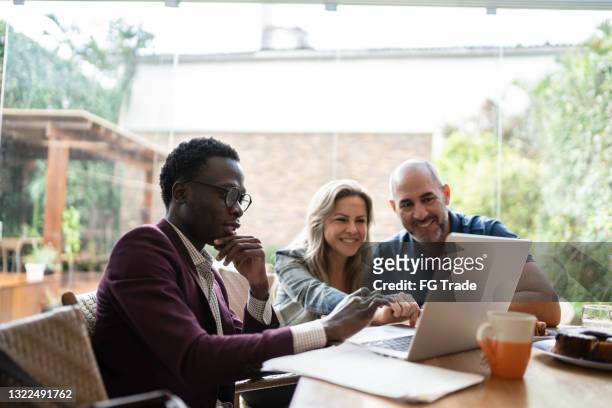 real estate agent or finance advisor doing a meeting with couple at home - insurance stock pictures, royalty-free photos & images