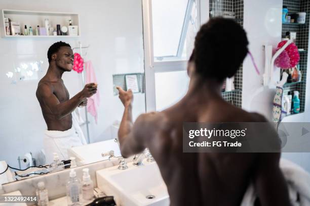 jovem feliz dançando em frente ao espelho de manhã em casa - enrolado em toalha de banho - fotografias e filmes do acervo