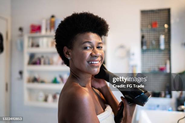 portrait of a mature woman blow drying her hair at home - adjusting hair stock pictures, royalty-free photos & images