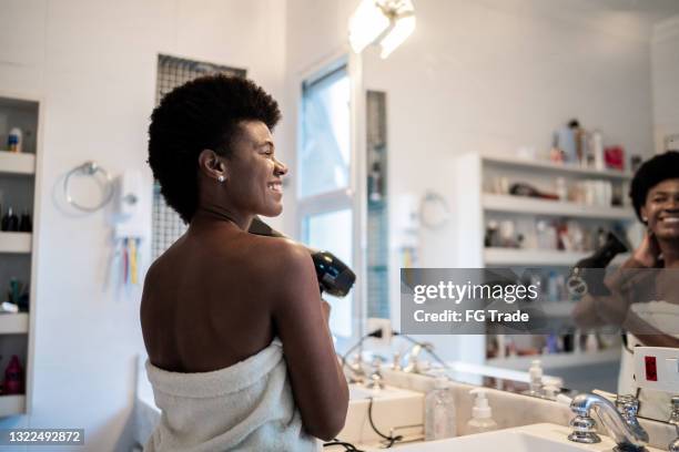 reife frau blasen trocknen afro haar zu hause - haare föhnen stock-fotos und bilder