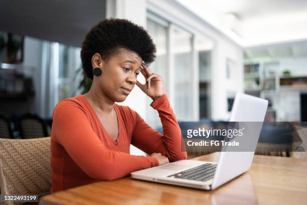 displeased mature woman doing a virtual business meeting at home - angry black woman stock pictures, royalty-free photos & images