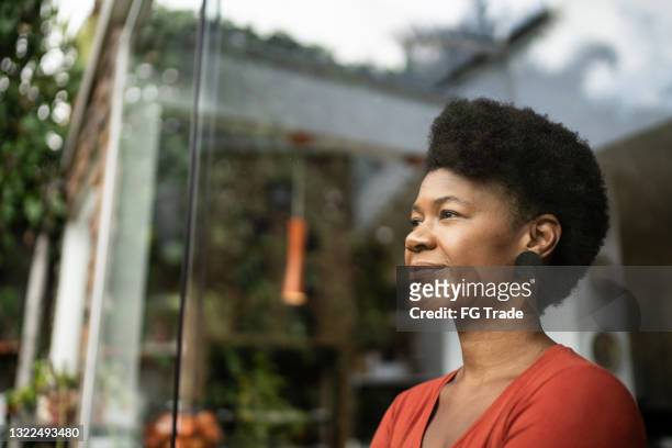 mature woman contemplating at home - motivatie stockfoto's en -beelden