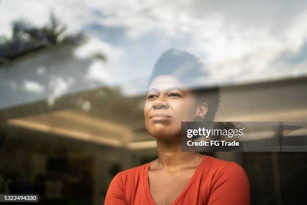 mature woman contemplating at home - black woman looking at view stock pictures, royalty-free photos & images