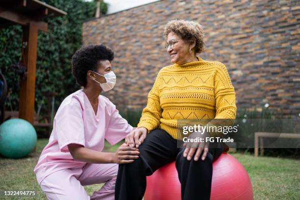 nurse with senior patient doing exercise at home - using protective face mask - senior physiotherapy stock pictures, royalty-free photos & images