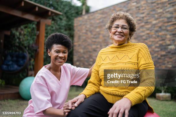 portrait of nurse and senior patient doing exercise at home - person of colour stock pictures, royalty-free photos & images