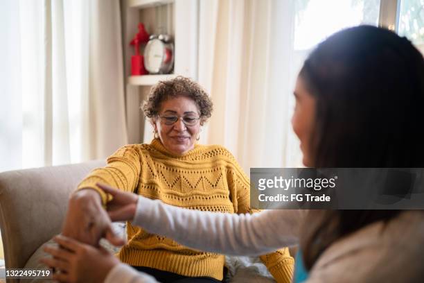 physical therapist helping senior woman doing exercise at home - person of colour stock pictures, royalty-free photos & images