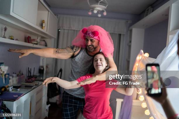 vater hat spaß beim tanzen mit töchtern und filmt es zu hause - mädchen mit besonderen bedürfnissen - father daughter dance stock-fotos und bilder