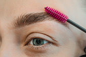 Combing, plucking eyebrows close-up. Close up of woman doing her make up, preparing brows using brush tool brushing eyebrows.