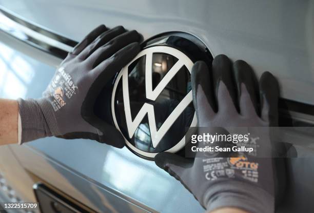 Worker affixes the VW hood ornament to a Volkswagen ID.3 electric car on the assembly line at the "Gläserne Manufaktur" production facility on June...