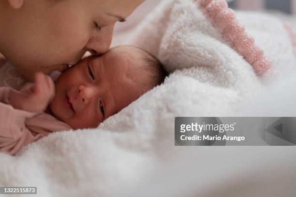 junge mutter küsst ihr neugeborenes baby, während sie in seiner krippe liegt - good night kiss stock-fotos und bilder