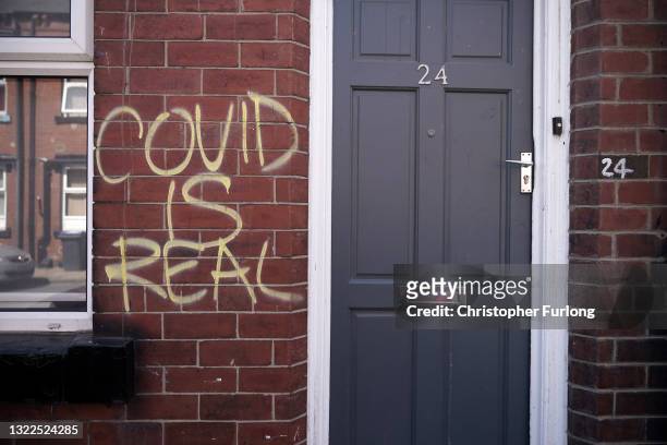 Graffiti declaring 'COVID IS REAL' is spray painted on the wall of a home in the Hyde Park area on June 08, 2021 in Leeds, United Kingdom.