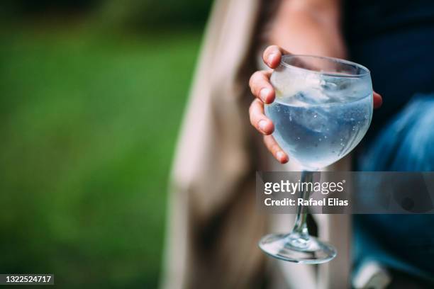 hand holding gin and tonic glass - gin and tonic stock pictures, royalty-free photos & images