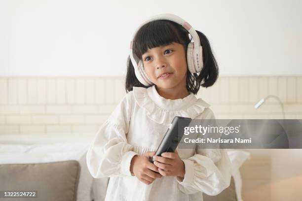 asian little child girl is singing and dancing on the bed at home. - vip room stock pictures, royalty-free photos & images