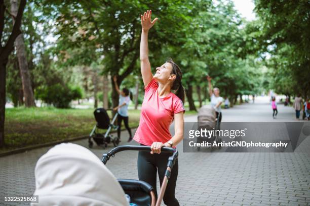 young mothers training in public park with their babies. - mother stroller stock pictures, royalty-free photos & images