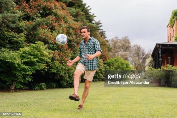 man playing soccer on the backyard lawn - rematar à baliza imagens e fotografias de stock