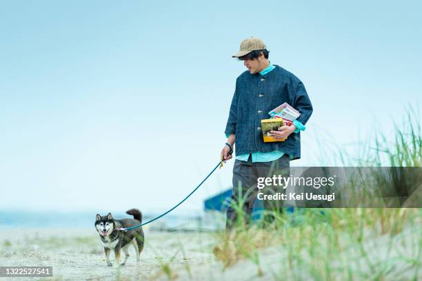 man and dog walking along the beach - shiba inu fotografías e imágenes de stock