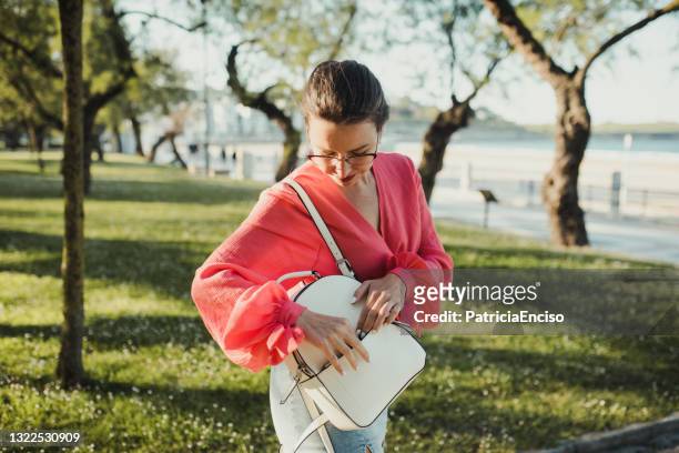 ung kvinna söker i sin handväska - purse bildbanksfoton och bilder