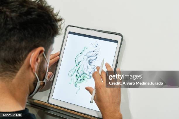tattoo artist with mask designing tattoo on a tablet. - artists with animals stock pictures, royalty-free photos & images