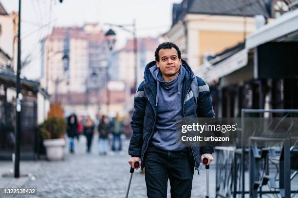 mens die lopende wandelkanten voor het lopen van gewonde binnenstad met behulp van - crutches stockfoto's en -beelden
