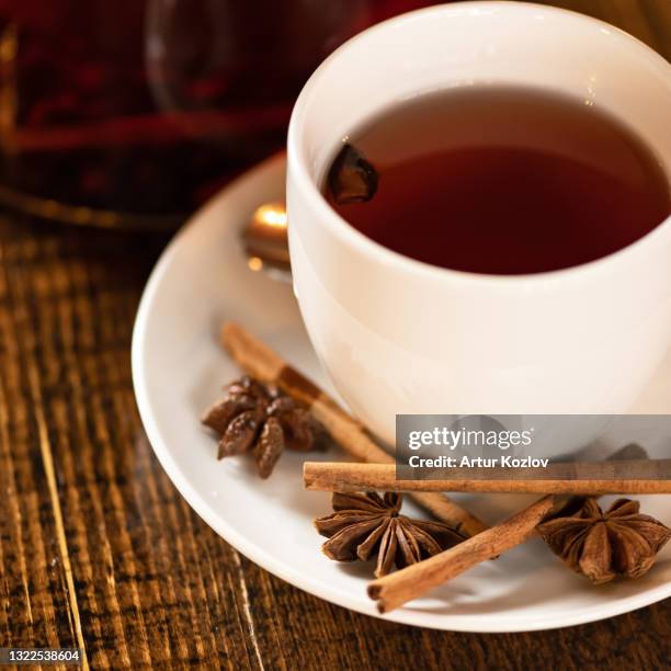 cup of black tea with anise and cinnamon spices. close up shot. square format. selective focus on foreground - anise plant stock pictures, royalty-free photos & images