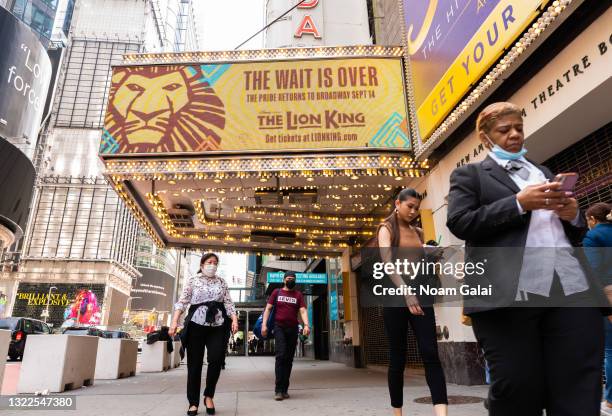 People walk by a billboard for The Lion King at the New Amsterdam Theatre in Times Square on June 08, 2021 in New York City. On May 19, all pandemic...