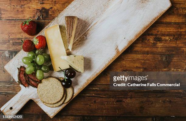 top-down image of a delicious, simple cheese board on a wooden table - cutting board stock pictures, royalty-free photos & images