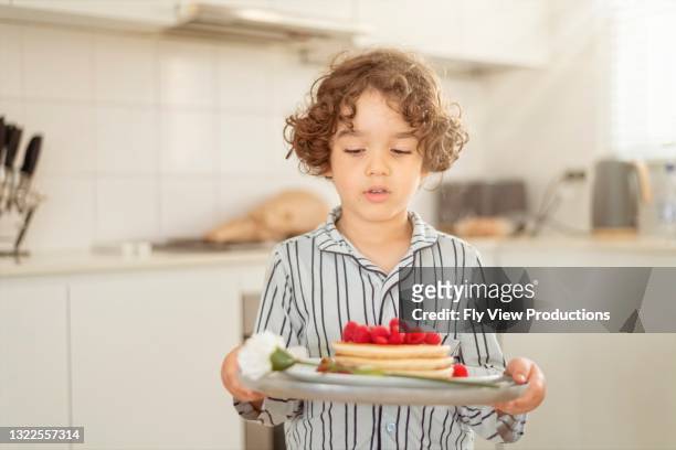 bellissimo bambino che porta un vassoio pieno di pancake per sua madre la festa della mamma - pancake day foto e immagini stock