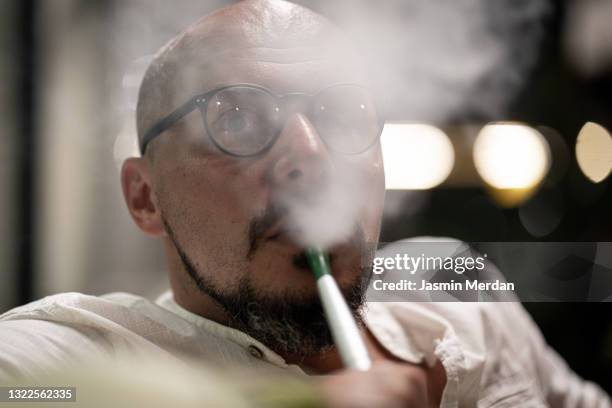 man smoking hookah at coffeeshop at night - hookah imagens e fotografias de stock