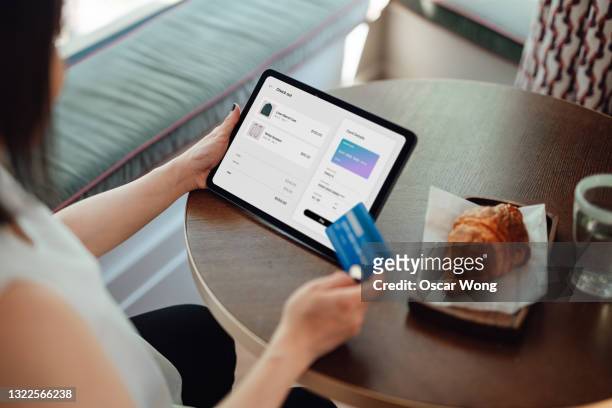 young woman making credit card payment while doing online shopping on digital tablet - credit card mockup stock-fotos und bilder
