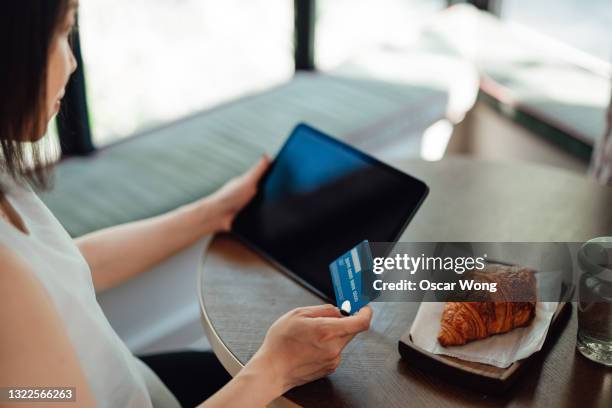 young woman making credit card payment while doing online shopping on digital tablet - credit card mockup stock-fotos und bilder