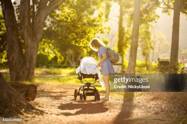 mom covering her baby in a stroller while walking in a park - carrinho de criança imagens e fotografias de stock