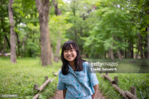 portrait of happy teenage girl standing on footpath in forest - japan 12 years girl stock pictures, royalty-free photos & images