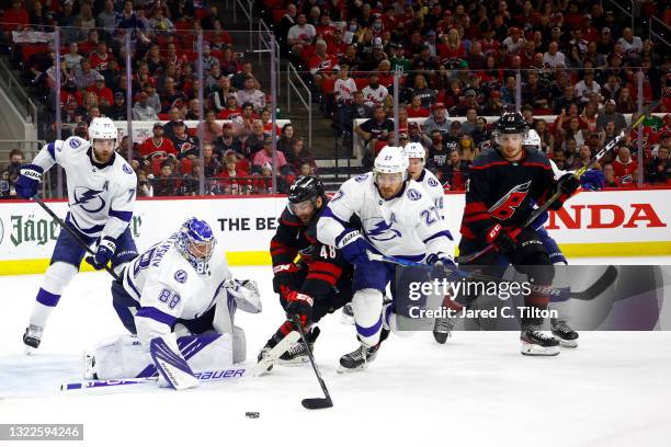 Jordan Martinook of the Carolina Hurricanes attempts a shot against Andrei Vasilevskiy and Ryan McDonagh of the Tampa Bay Lightning during the third...