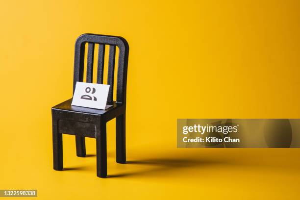 empty chair with a people icon sign on it against yellow background - silla vacía fotografías e imágenes de stock