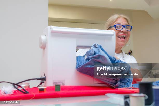 portrait of mature tailor sewing clothes and jeans at home - tee reel stock pictures, royalty-free photos & images